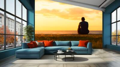 Thoughtful man sitting watching the sunset.  Wall mural