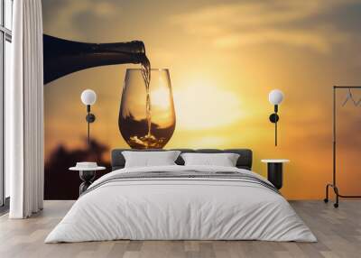 Wine pouring into glass on sunset background.  Wall mural