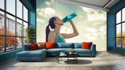 Woman drinking bottle of water outdoor on a hot summer day. Wall mural