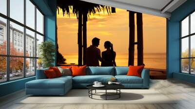 Young couple watching the sunset form hotel porch. Tropical romantic getaway concept. Wall mural