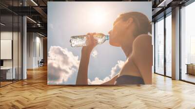 Young female drinking bottle of water on a hot sunny day.  Wall mural