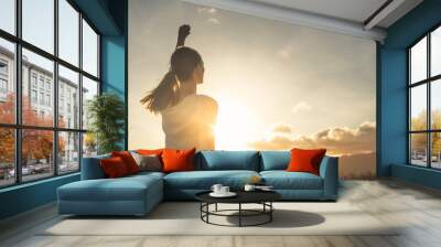 Young female outdoors with fist in the air feeling strong and confident. Victory and success concept.  Wall mural