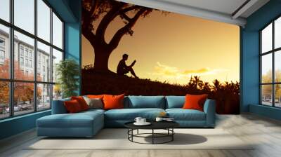 Young man reading a book in the park. Learning, reading, and education concept.  Wall mural