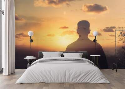 Young thoughtful man on a mountain facing the sunrise. Life vision, and mental health concept.  Wall mural