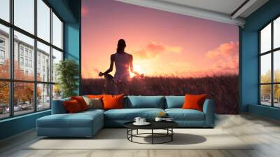 young woman meditating outdoors at sunset. Wall mural