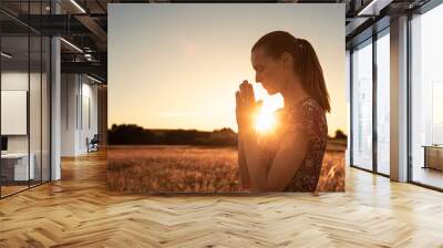 Young woman praying outdoors in the morning light. Religious worship, and spiritual enlightenment concept. 	 Wall mural