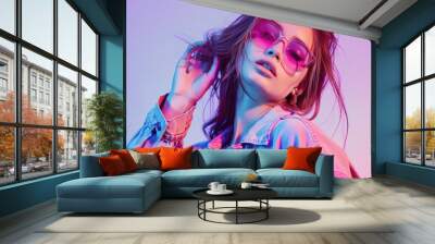 A fashion model poses in an urban setting, wearing sunglasses and trendy against a pastel purple background Wall mural