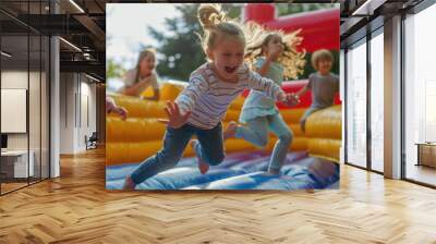 A group of children are having fun on an inflatable bouncy castle in the sun Wall mural