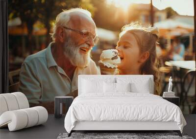 A happy grandfather and his smiling little girl eating ice cream at an outdoor cafe on a summer day with the sun shining and warm colors Wall mural