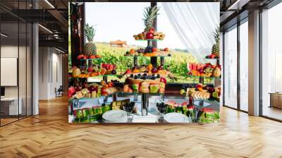 Fruit buffet for a wedding. Assortment of exotic fruits on the background of vineyards in the restaurant. Decoration of fresh fruit. Wall mural