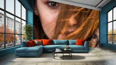 Young adult woman's with one eye covered with hair focus on her brown big eye. Wall mural