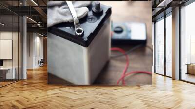 Changing a car battery. Automotive battery on a work desk with testing probe and wrenches in background. Focus on foreground. Wall mural