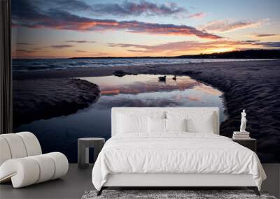 a stream leads out to a lake during sunset with reflections in the water and two ducks swimming in the stream Wall mural