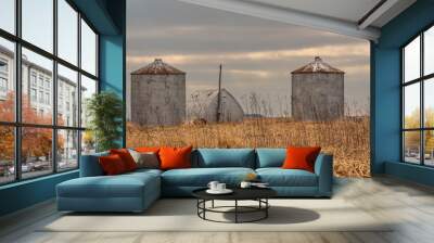 Two small, round, metal grain bins and an unusual shaped, arched metal building with an electric pole. Wall mural