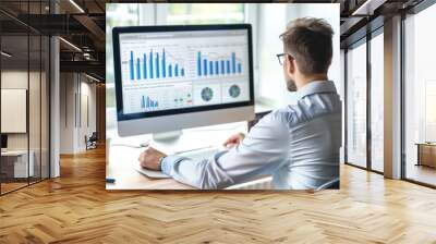 A businessman analyzing website traffic and engagement metrics on a computer screen. Wall mural