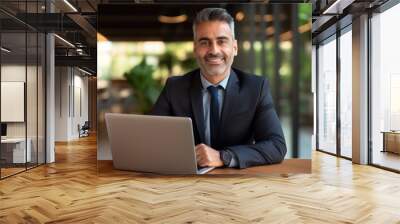 Portrait of mature Indian or Latin business man ceo trader using laptop computer, typing, working in modern office. Middle-age Hispanic smiling handsome businessman entrepreneur looking at camera  Wall mural