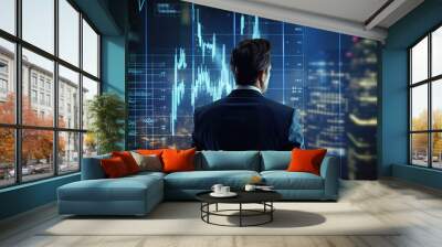 Well-dressed man is standing in front of a large stock chart screens and monitoring the market. Wall mural