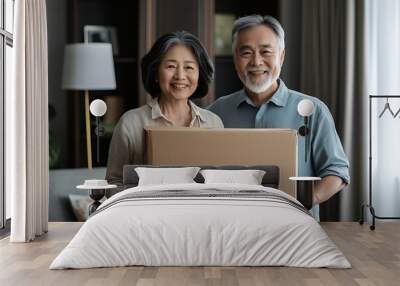 A happy elderly couple holding a cardboard box in a cozy living room. Wall mural