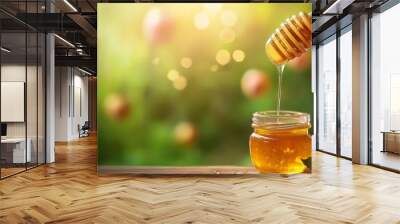 A jar of honey with a honey dipper, surrounded by a natural, blurred background. Wall mural