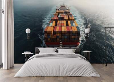 An aerial view of a cargo ship sailing on the open ocean, with a row of colorful shipping containers stacked on its deck. Wall mural