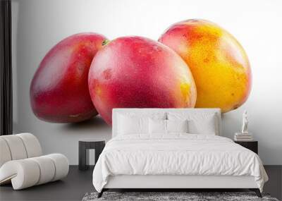 Three ripe mangoes, two red and one yellow, on a white background. Wall mural