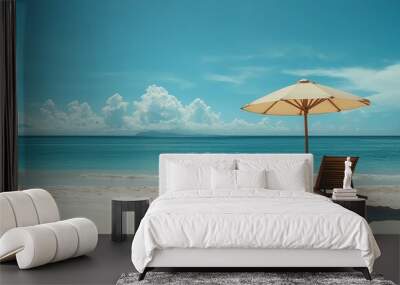 Two beach chairs sit under an umbrella on a sandy beach facing the ocean. Wall mural