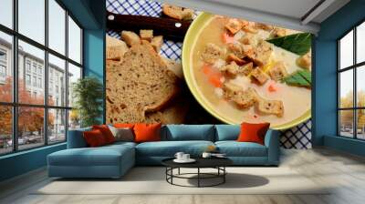 Vegetable soup with sausage and pieces of bread on a blue checkered napkin Wall mural