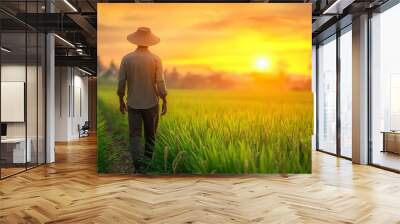 Farmer standing in rice field at sunset with golden sky Wall mural