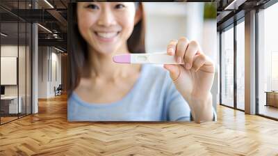 Closeup Asian woman hand holding positive pregnancy test, Two stripes on test.  Wall mural