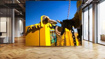 Close up industrial rigger high risk worker hand wearing safety heavy duty glove and clipping a crane hook into yellow crane lifting gate prior lifting in Construction site Perth city, Australia  Wall mural