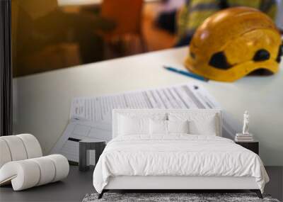 Defocused personal protective equipment safety helmet head protection placing on the table with working at height rescue plan paperwork at the foreground    Wall mural