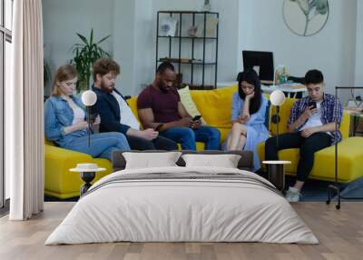 A multiethnic group of young people of different ages working with smartphones in a modern office Wall mural