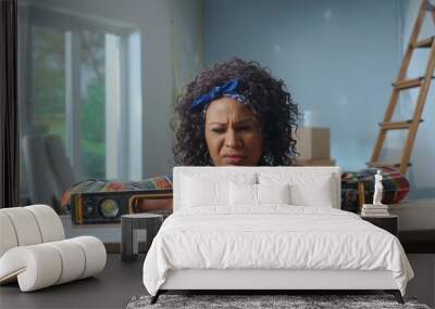 A young African American woman poses next to a building bubble level on a table. The black woman looks at the level in confusion. The concept of repair, finishing work, interior design. Wall mural