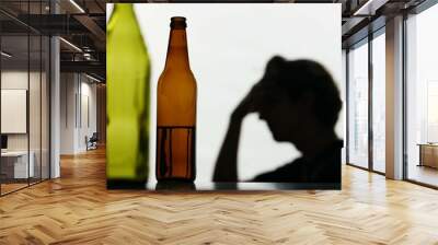 In the close-up shot, there are empty, broken glass bottles full of alcohol. In the background, the man is strong he is very sad, sad, sad. Demonstrates the struggle with addiction. Wall mural