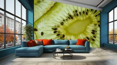 Macro shot of fresh juicy green kiwi slice against skylight, showing flesh and seeds with watery texture structure of fruit visible under light. Wall mural