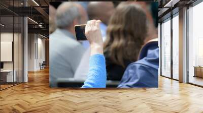 Hand of a person filming an event performance on a smartphone Wall mural