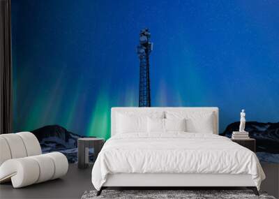 Telecommunication tower with 5G cellular network antenna on night winter landscape with aurora green northern lights Wall mural