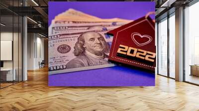 concept - Inscription 2022 on the mock-up of a black house lies on a stack of money on a purple background Wall mural