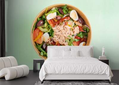 Fish diet salad with tuna, tomatoes, arugula on green background. Healthy lunch, top view. Eco-friendly carton packaging, environment protection. Food delivery in disposable plate of craft paper. Wall mural