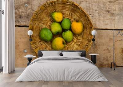 Mango in a wooden basket against a wooden table background Wall mural