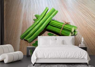 Moringa Oleifera or drumstick vegetable with leaves on wooden background Wall mural