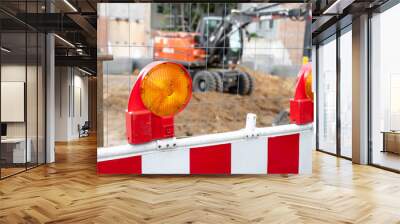 Close-up detail view orange flasher safety blinker light barrier against fence construction site work area. Security equipmnent barricade fuse lamp city street building construction machinery traffic Wall mural