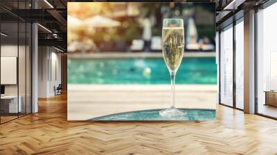 Close-up white champagne or prosecco glass against poolside at luxury resort hotel during vacation. Sparkling wine with rising bubbles with blue pool background outdoor. Refreshing alcohol drink Wall mural