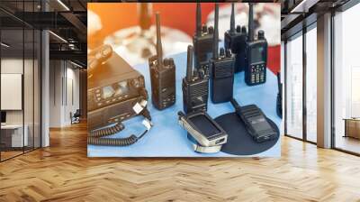 Many portable radio transceivers on table at technology exhibition. Different walkie-talkie radio set. Communication devices choice for military and civil use Wall mural