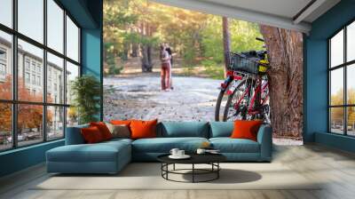 Scene view of young adult lovers pair enjoy hugging at outdoors forest walk date with bicycles. Sport lifestyle healthy recreation leisure bike tour trip in nature woods at autumn evening together Wall mural