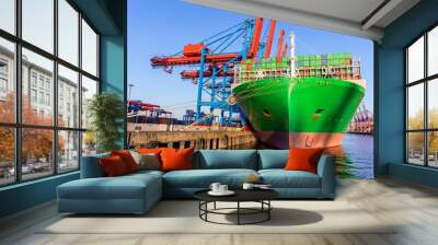 Scenic view giant cargo container ship loading Hamburg city port harbor against seaport cranes warm evening sunset lights. Global commercial trade freight charter shipping and logistics background Wall mural