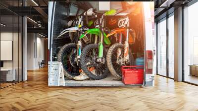 Three bright dirty sport motocross motorcycles stand in tail of technical support assistance van in team camp during extreme offroad championship. Mobile cycle service, maintenance transport concept Wall mural