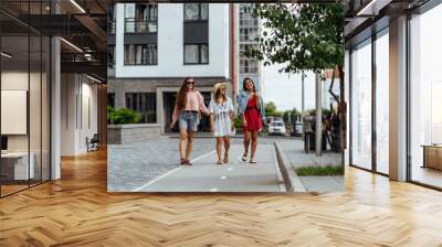 Outdoor shot of three young women having fun on city street. Beautiful female friends enjoying a day around the city. Wall mural