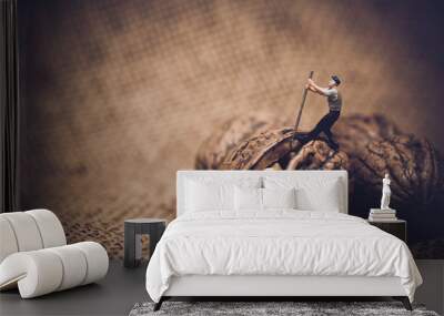 Miniature worker with a crowbar trying to open a walnut Wall mural