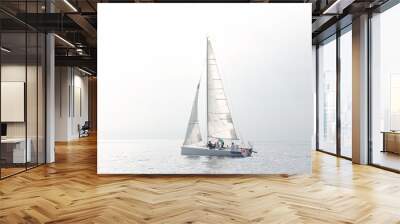 Sailing team adjusting sails on yacht during regatta on calm sea Wall mural